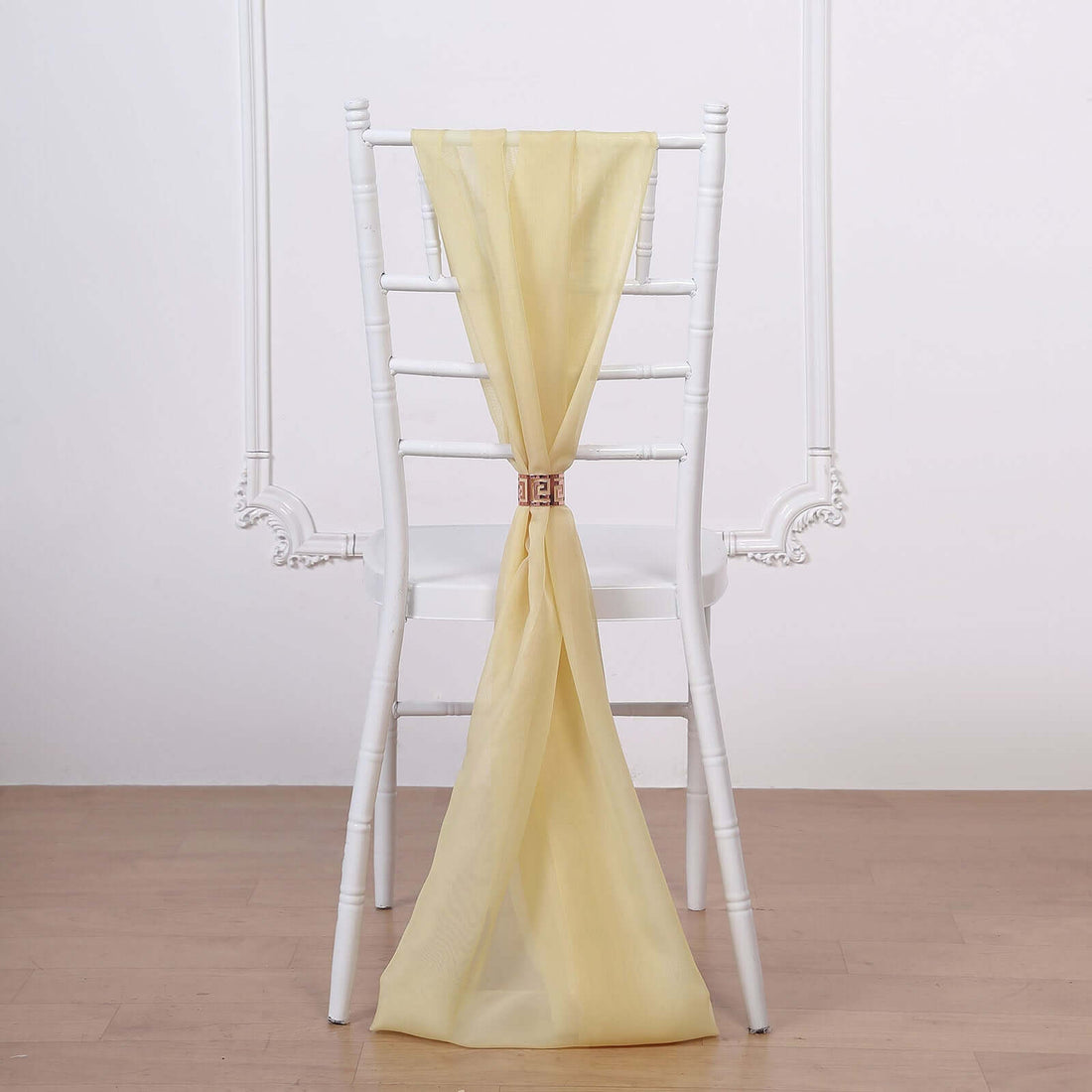 Yellow chiffon chair sash tied on a white chiavari chair.
