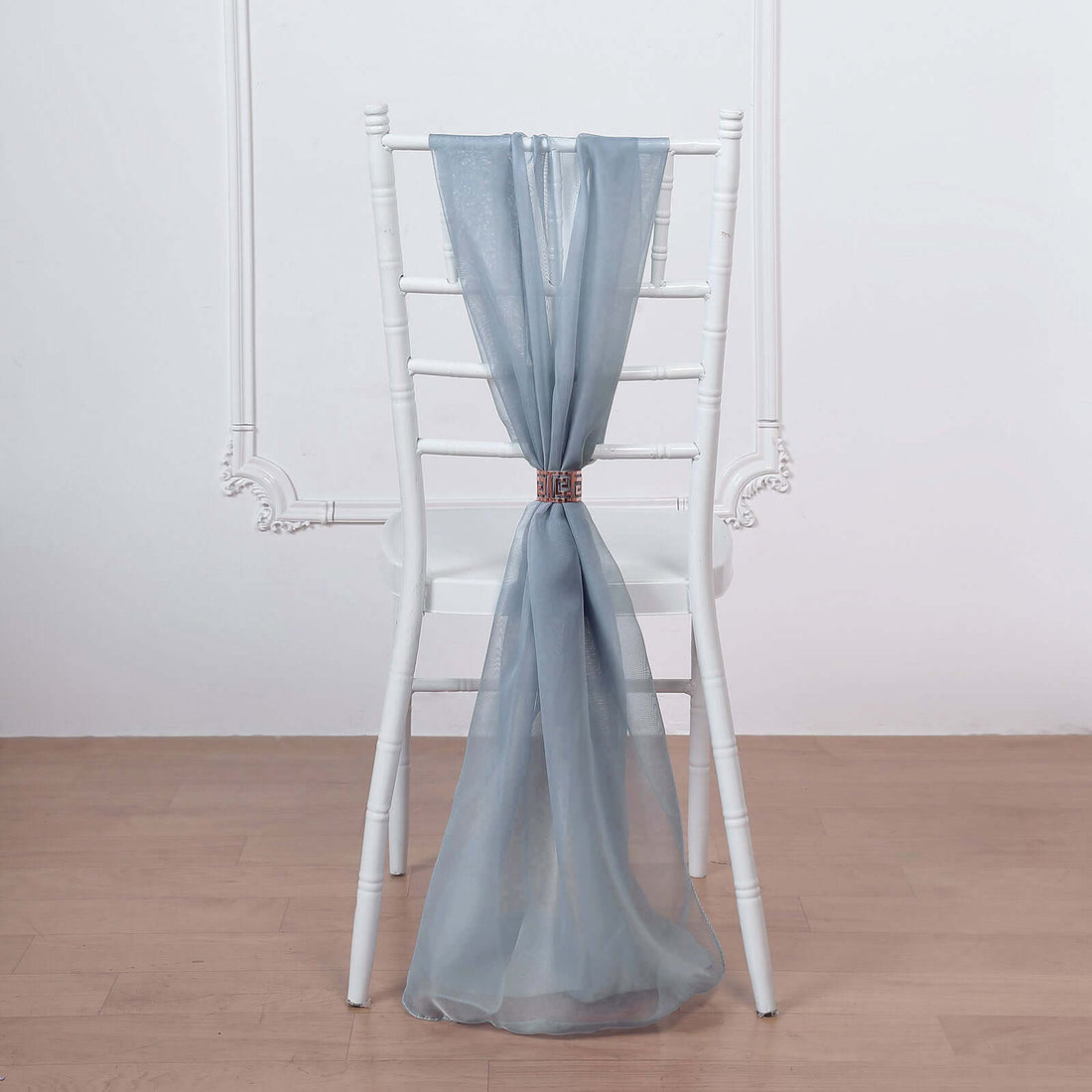 Sheer blue curtain draped over a white chair in a minimalist setting.