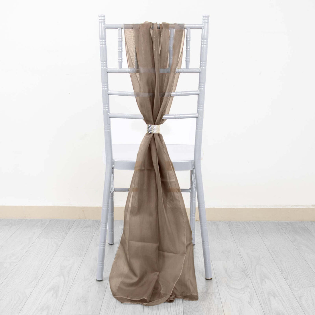 Brown sheer fabric draped on a grey chiavari chair.