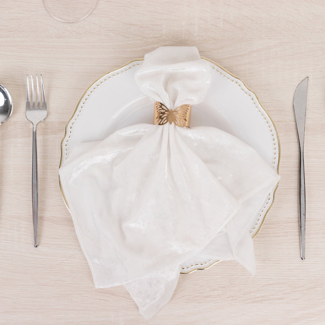 Elegant white napkin with butterfly holder on a decorative plate.