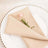 Elegant beige napkin folded with a pink flower on a decorative plate.