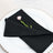 Black cloth napkin elegantly folded with a pink flower on a decorative plate.