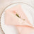 Pink napkin with a flower on a decorative plate.