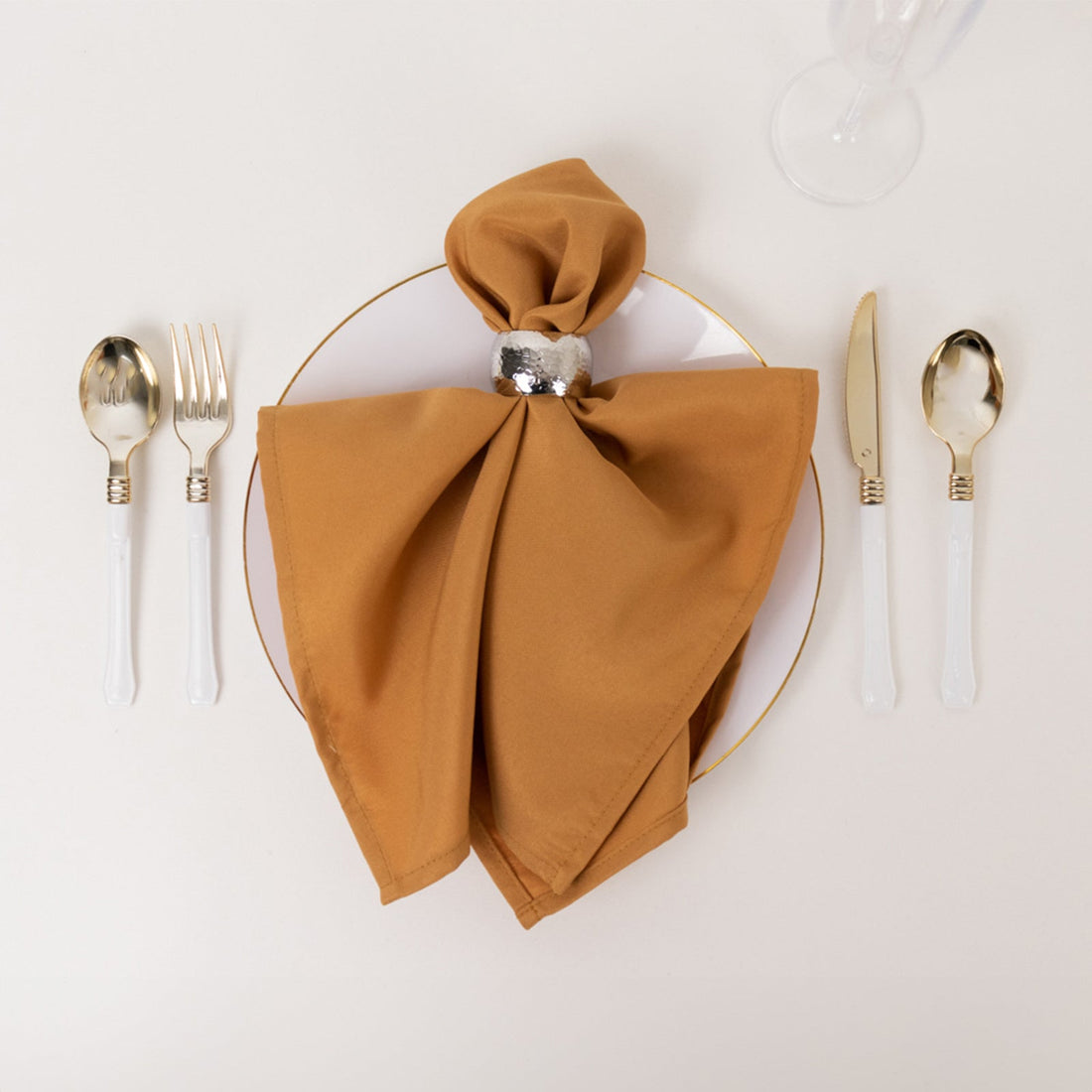 Elegant table setting with a gold napkin and silver cutlery.