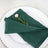 Green napkin elegantly folded on a decorative plate with a pink flower accent.