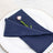 Navy blue napkin elegantly folded with a pink flower on a white plate.