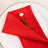 Red napkin elegantly folded on a plate with a small pink flower accent.