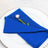Blue cloth napkin elegantly folded with a pink flower on a white plate.