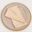 Beige cloth napkin folded on an elegant plate with a gold beaded rim.