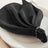 Elegant black napkin styled with beads on a white plate.