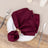 Burgundy fabric napkin elegantly styled on a white plate with cutlery.