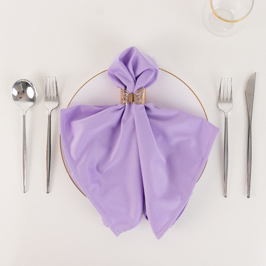 Lavender napkin elegantly folded with a gold ring on a dinner plate
