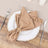Brown cloth napkin elegantly tied on a white plate with silver cutlery.