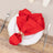 Red cloth napkin elegantly styled on a white plate, set on a rustic table.