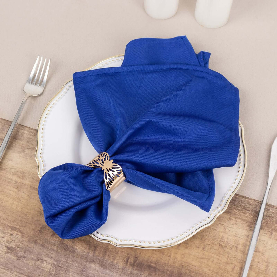 Elegant blue napkin with decorative ring on a white plate.