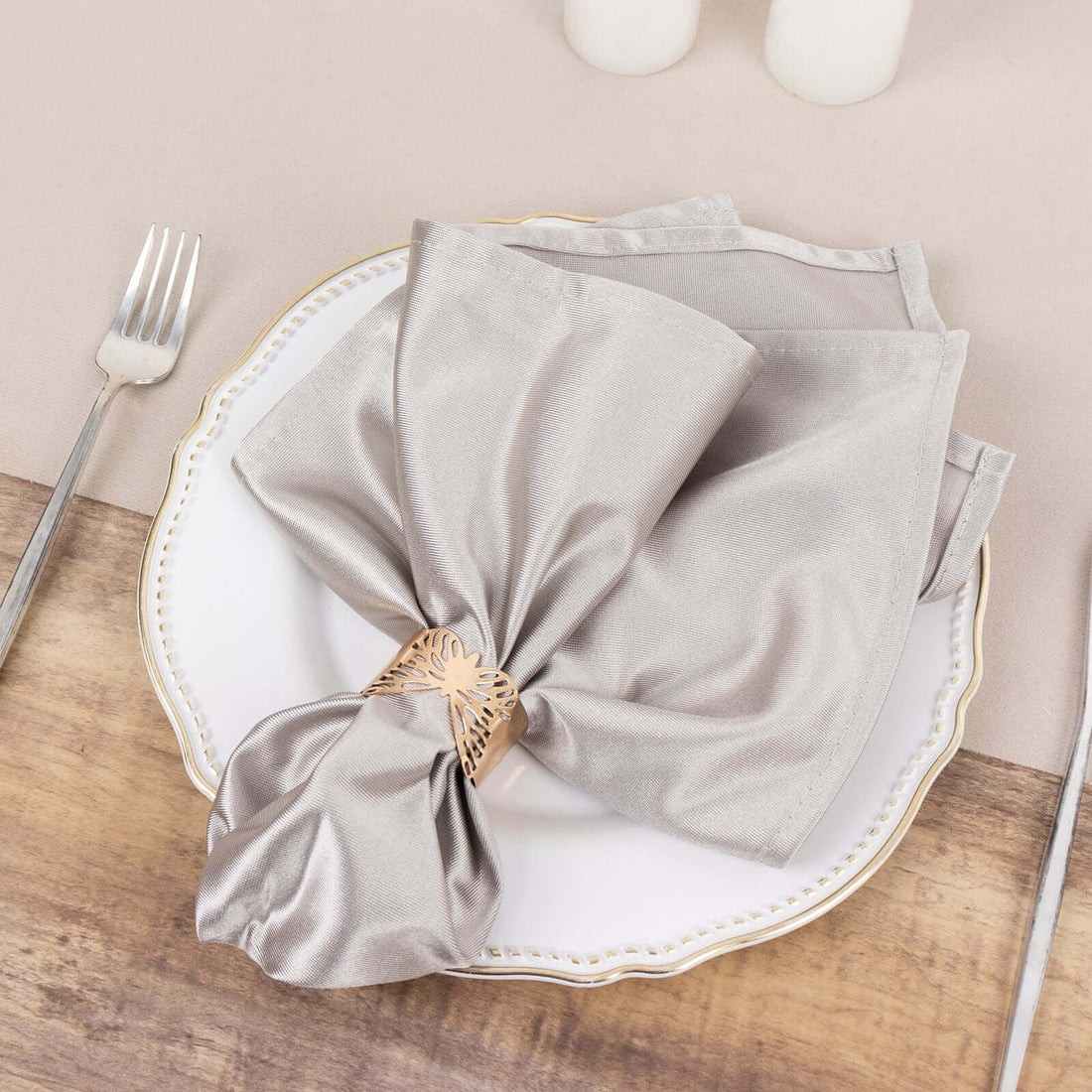 Elegant silver napkin tied with a decorative ring on a decorative plate.
