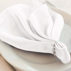 Elegant white napkin with decorative beading on a plate.