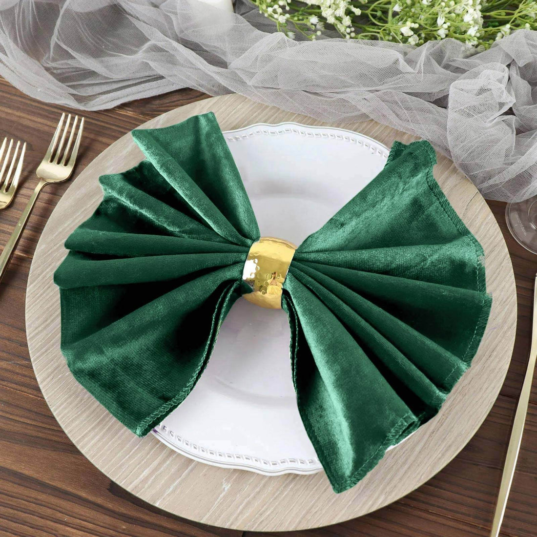 Green satin napkin bow on a decorative plate for elegant table settings.