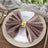 Elegant brown napkin with gold ring on a wooden table setting.