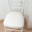 White padded chair with a sleek design and light wooden floor backdrop.