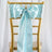 Light blue satin chair sash with bow and ring detail on a gold chair.