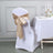White chair cover with a gold satin bow, styled for an elegant dining setting.