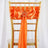 Orange satin chair sash with bow and ring detail.