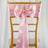 Pink satin chair sash with bow and ring detail on a gold chiavari chair.