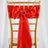 Red satin chair sash with a decorative ring, elegantly tied on a gold chair.