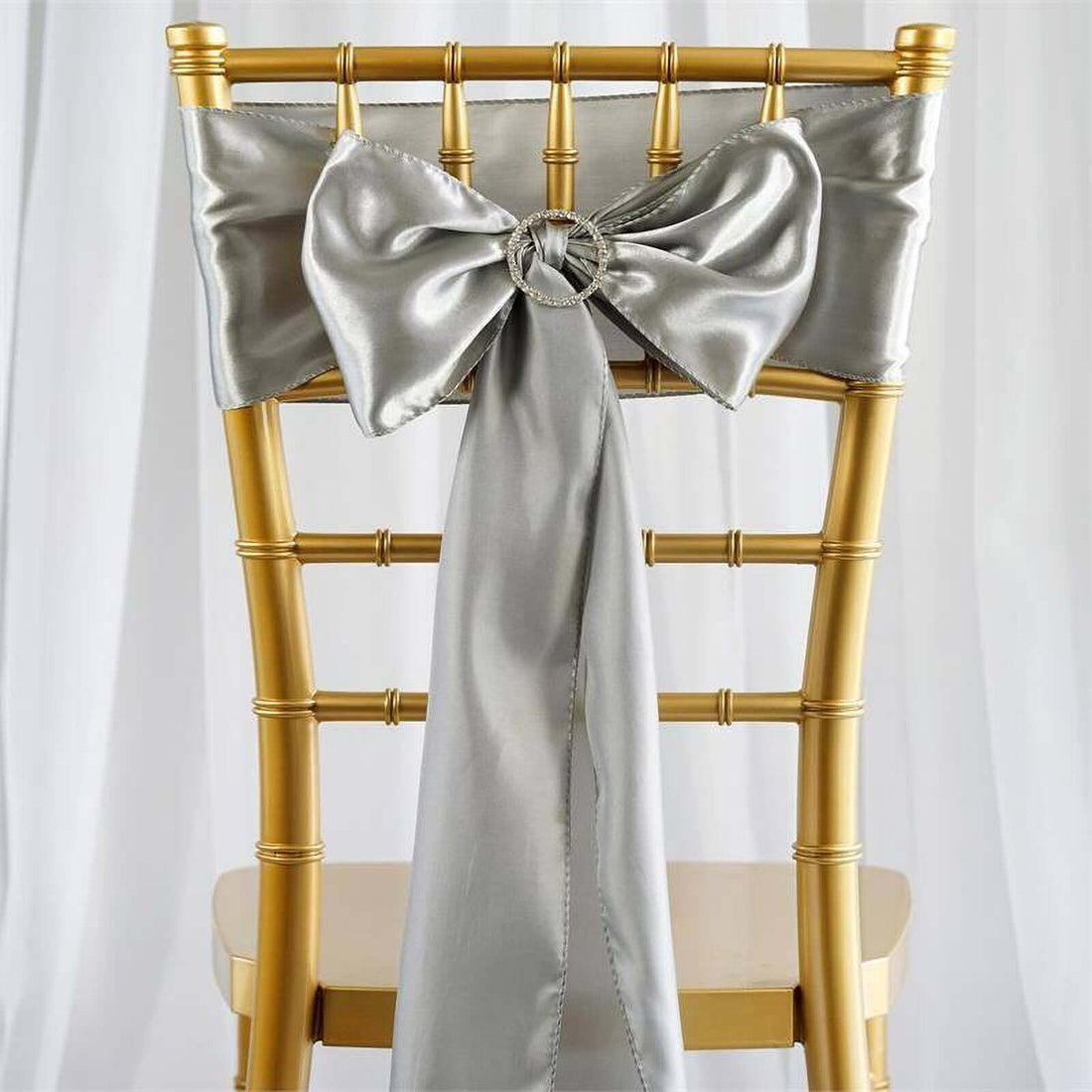 Silver satin chair sash with bow on a gold chiavari chair.