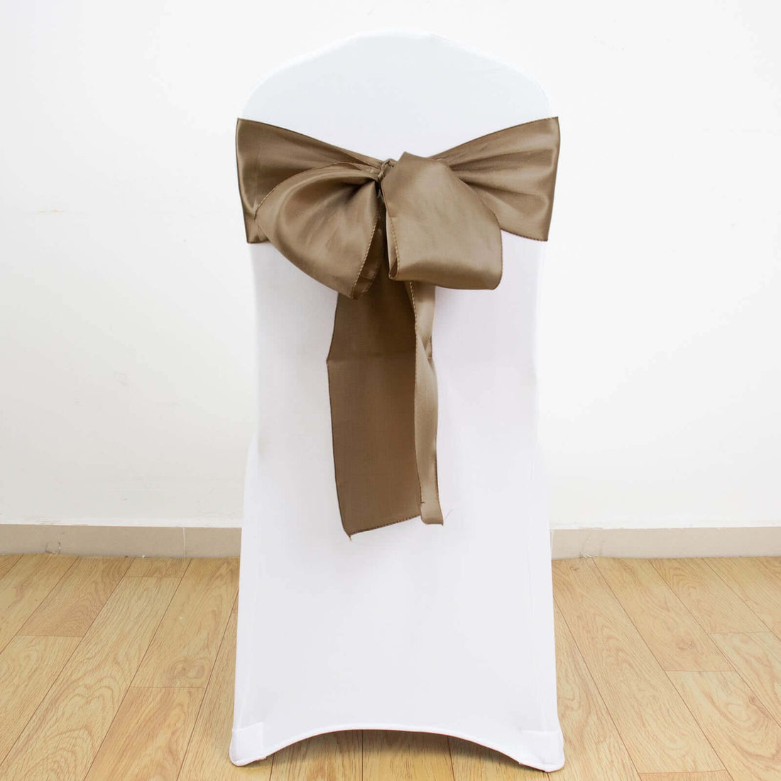 White chair with a brown satin bow tied on the back.