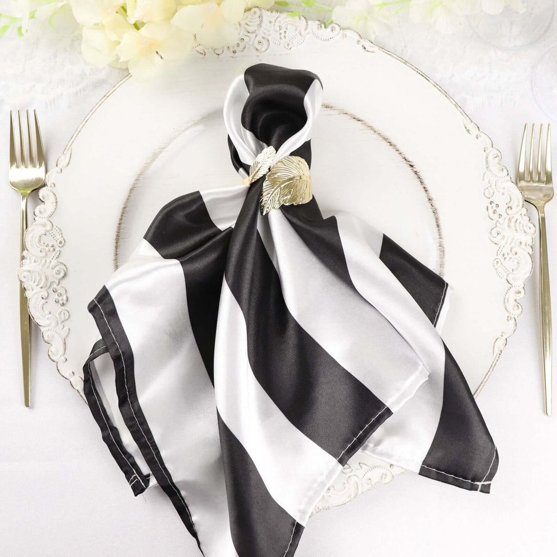 Black and white striped silk napkin elegantly arranged on a decorative plate.