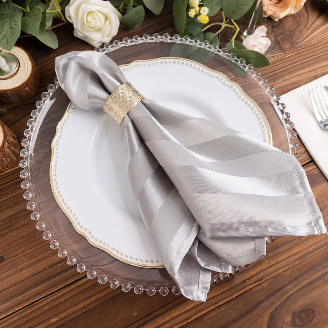 Elegant silver striped napkin with a decorative ring on a plate.