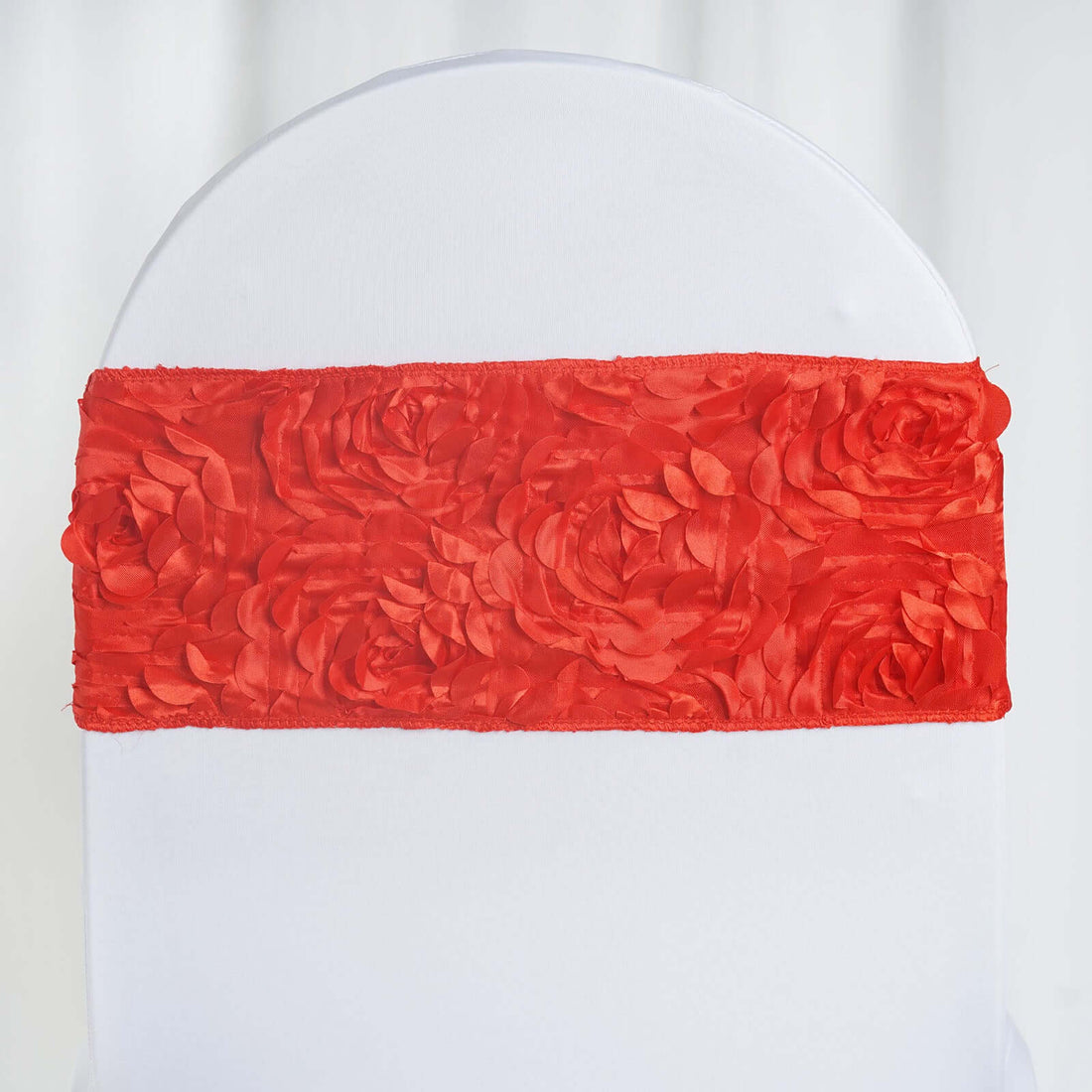 Red satin chair sash with floral design on a white chair.