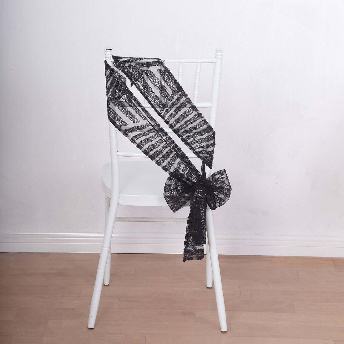 Black lace chair sash tied in a bow on a white chair.