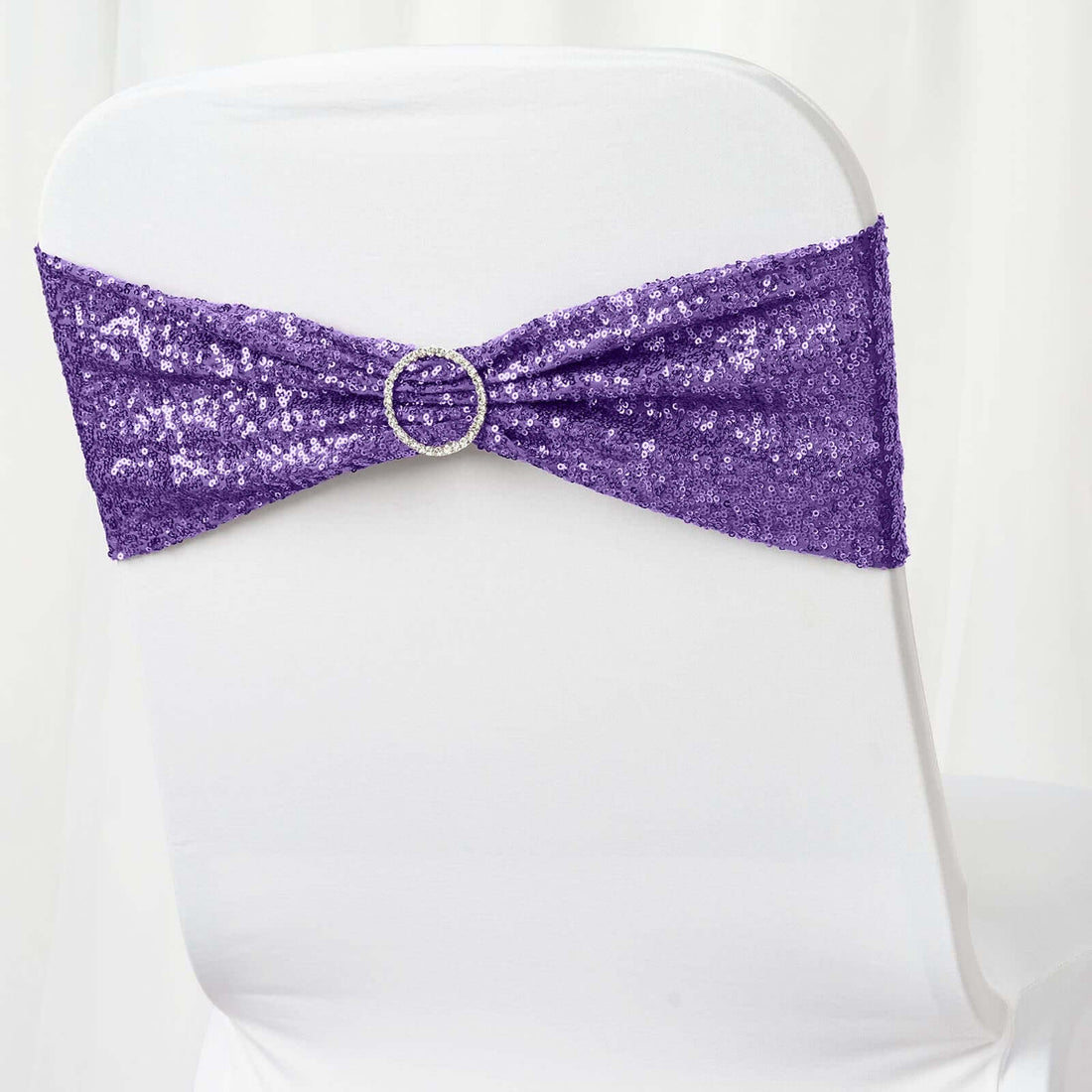Purple sequined chair sash with rhinestone buckle on a white chair.