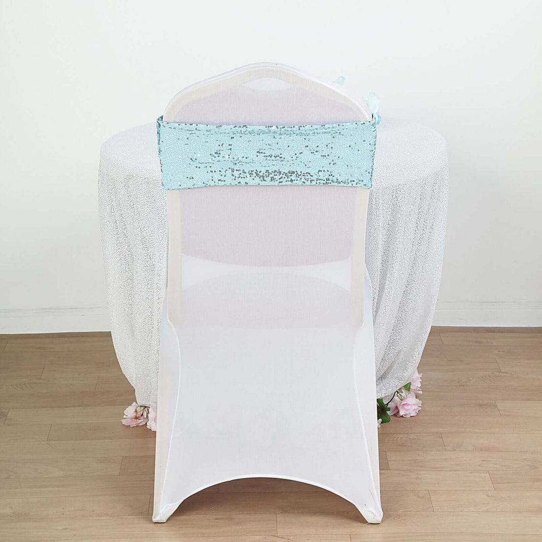 Sequin chair cover in light blue on a white chair against a plain backdrop
