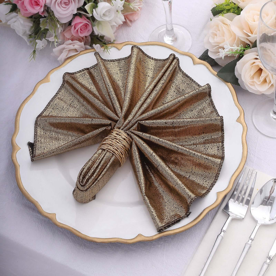 Elegant gold and brown napkin folded in a fan shape on a decorative plate.