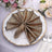 Elegant gold and brown napkin folded in a fan shape on a decorative plate.