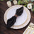 Black napkin elegantly styled on a decorative plate with gold accents.