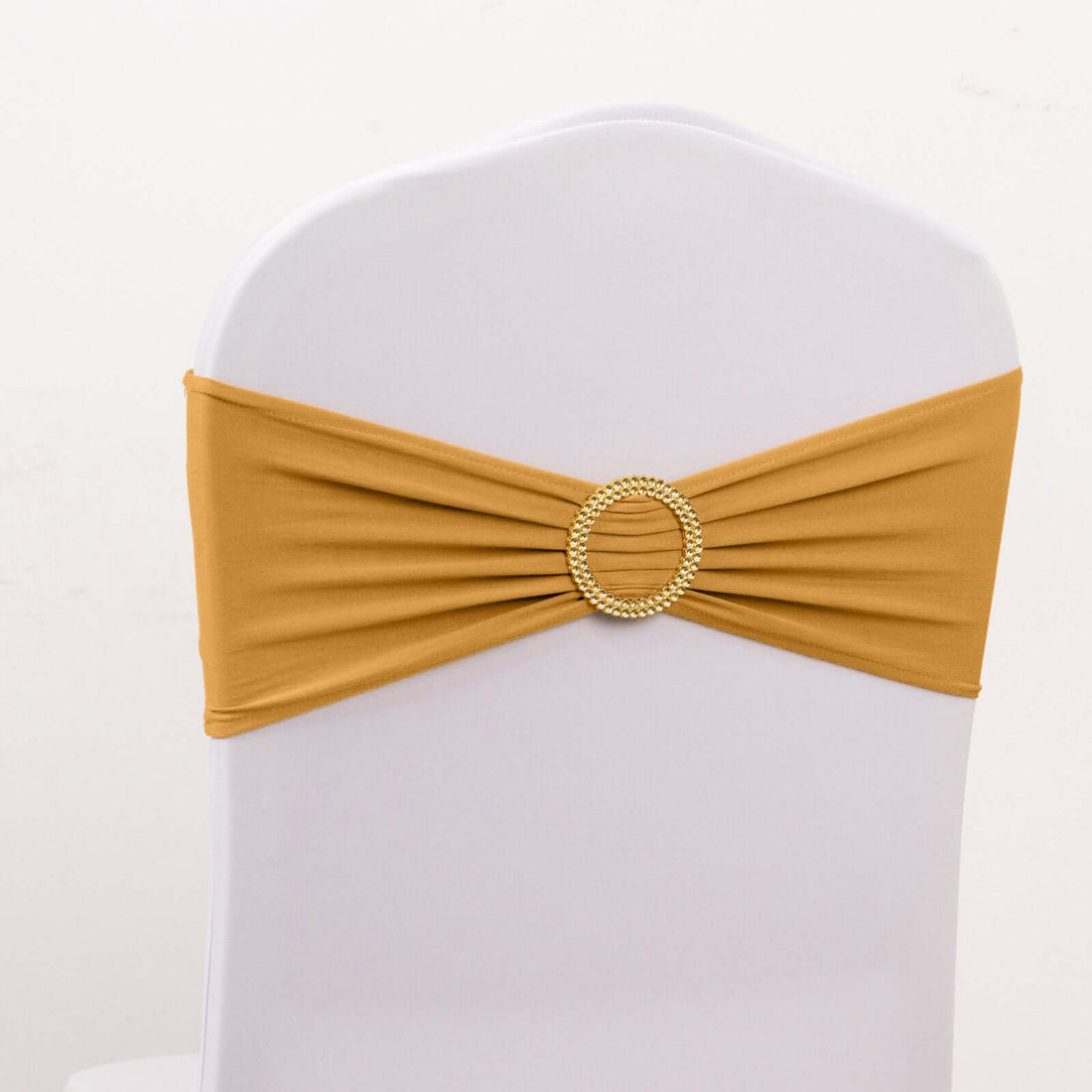 Gold chair sash with a decorative beaded buckle on a white chair.