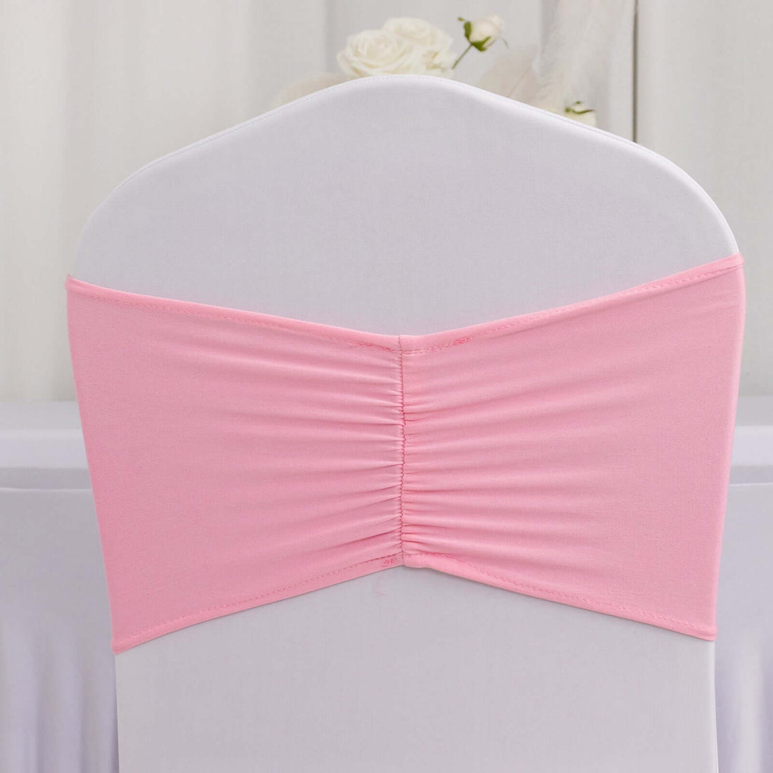 Pink chair cover back with gathered design for events or decorations.
