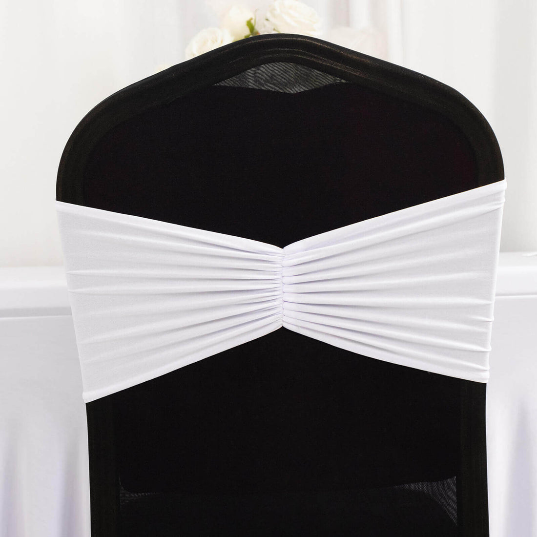 White chair cover sash on a black chair for elegant event decor.