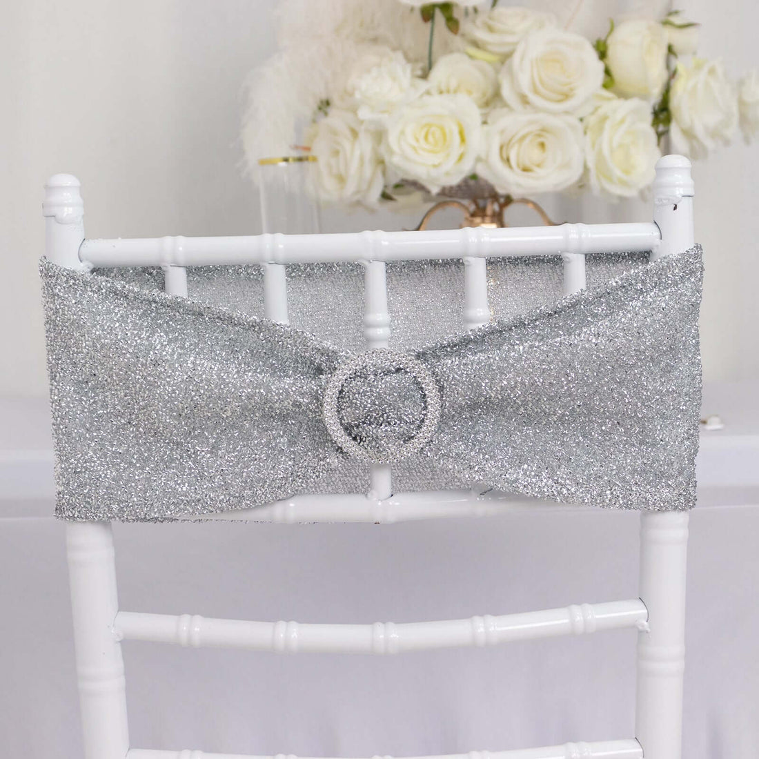 Silver glitter chair sash with rhinestone buckle on a white chiavari chair.