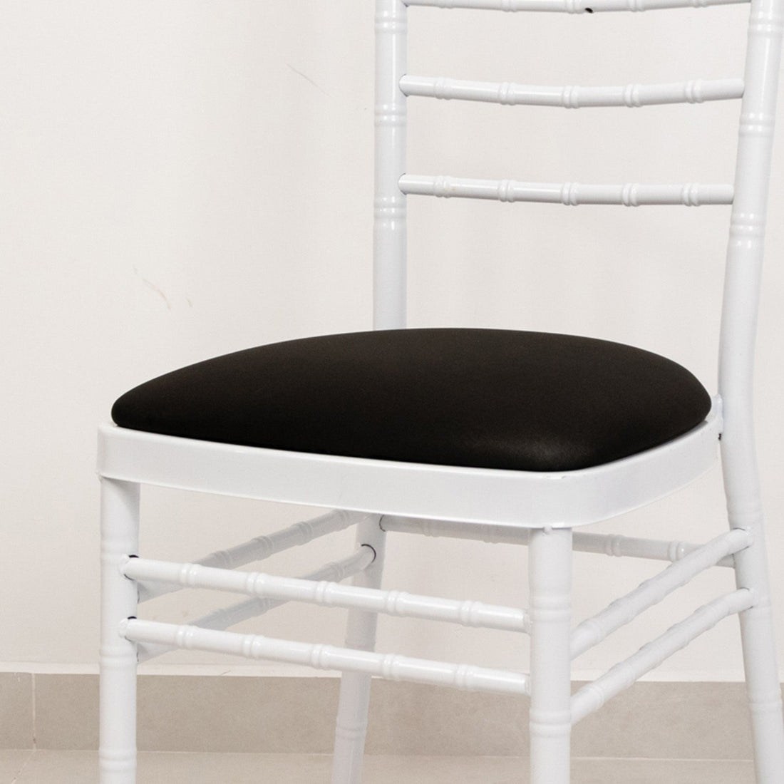 White chiavari chair with a black cushion seat.
