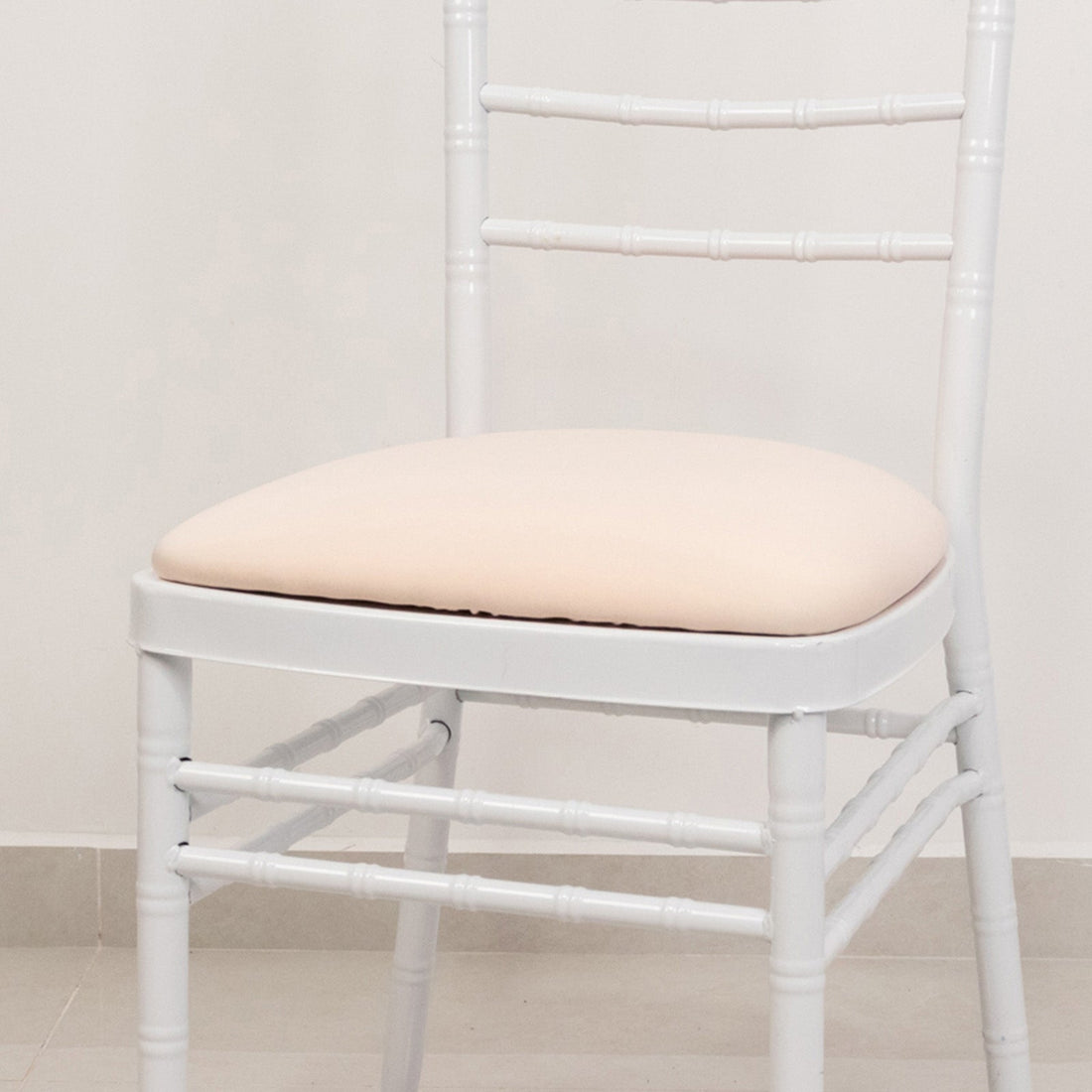 White chiavari chair with padded seat against a plain background.