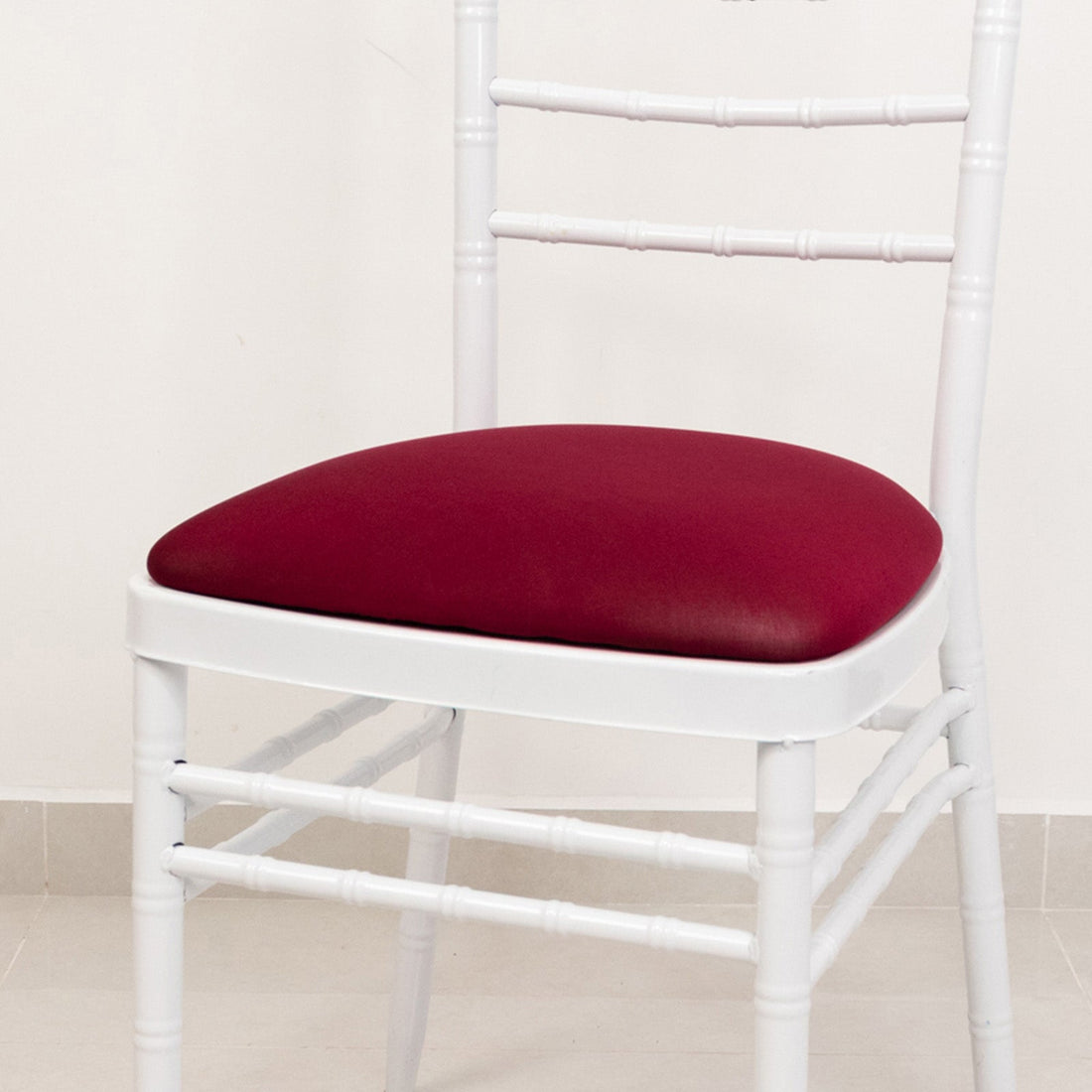White chiavari chair with burgundy cushion, studio shot.