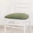 White chair with green cushion on a plain background.