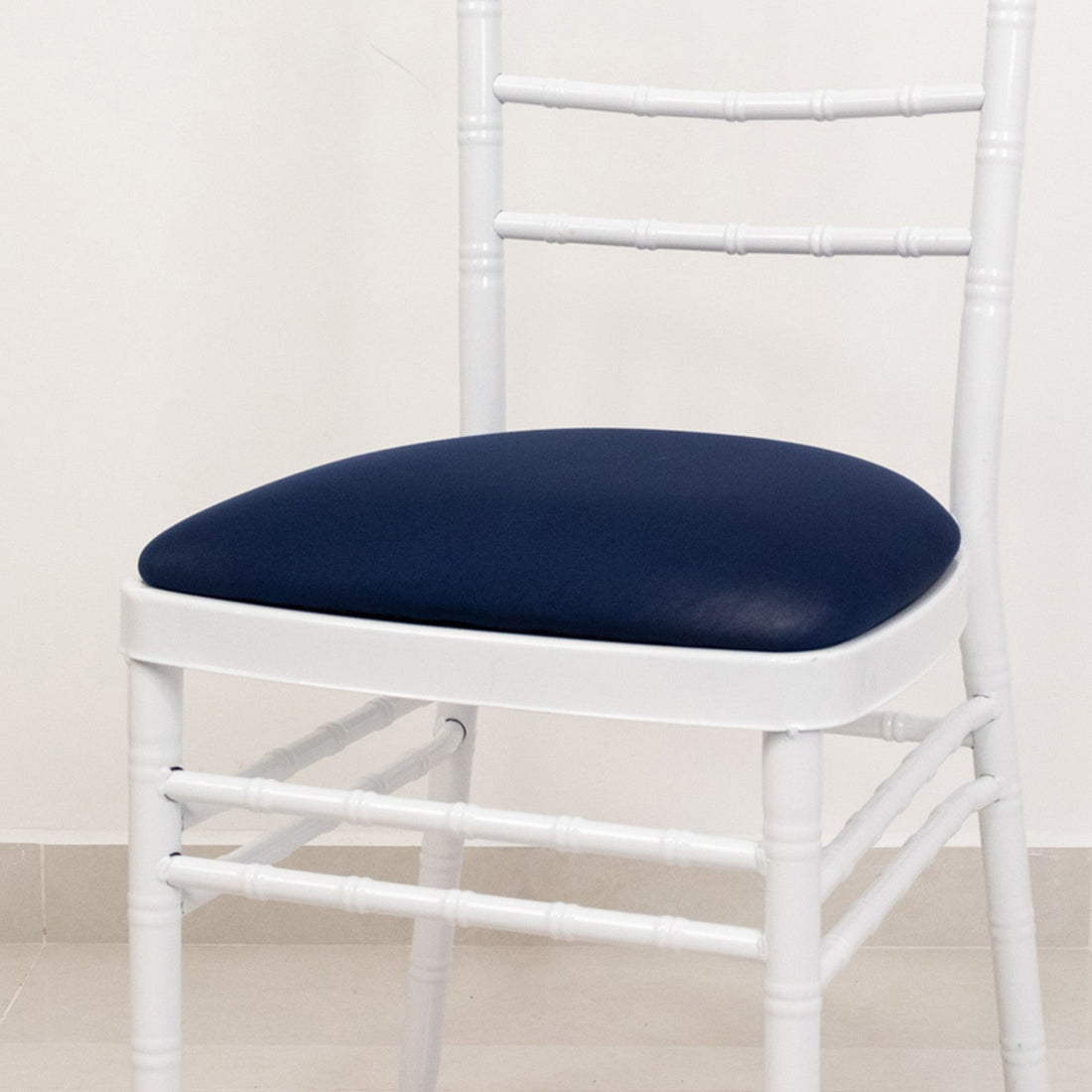 White chair with blue cushion on a plain background.