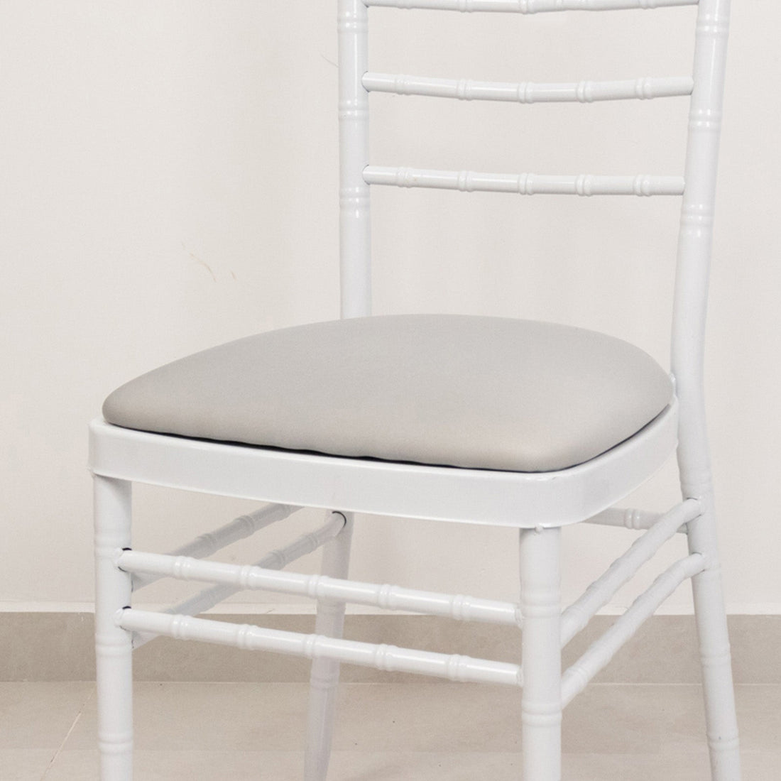 White chair with a padded gray seat on a neutral floor.